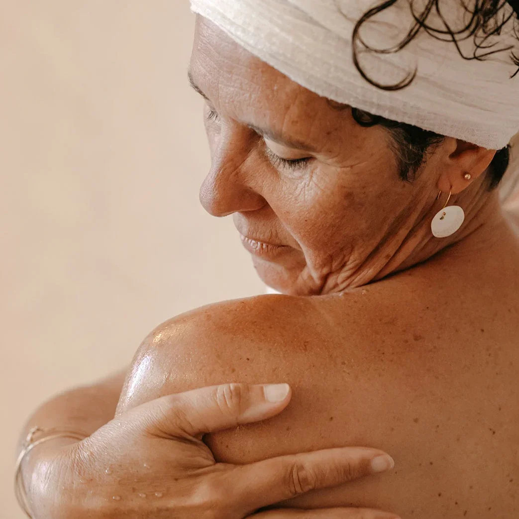 Femme qui applique l'huile sèche Dune sur son épaule
