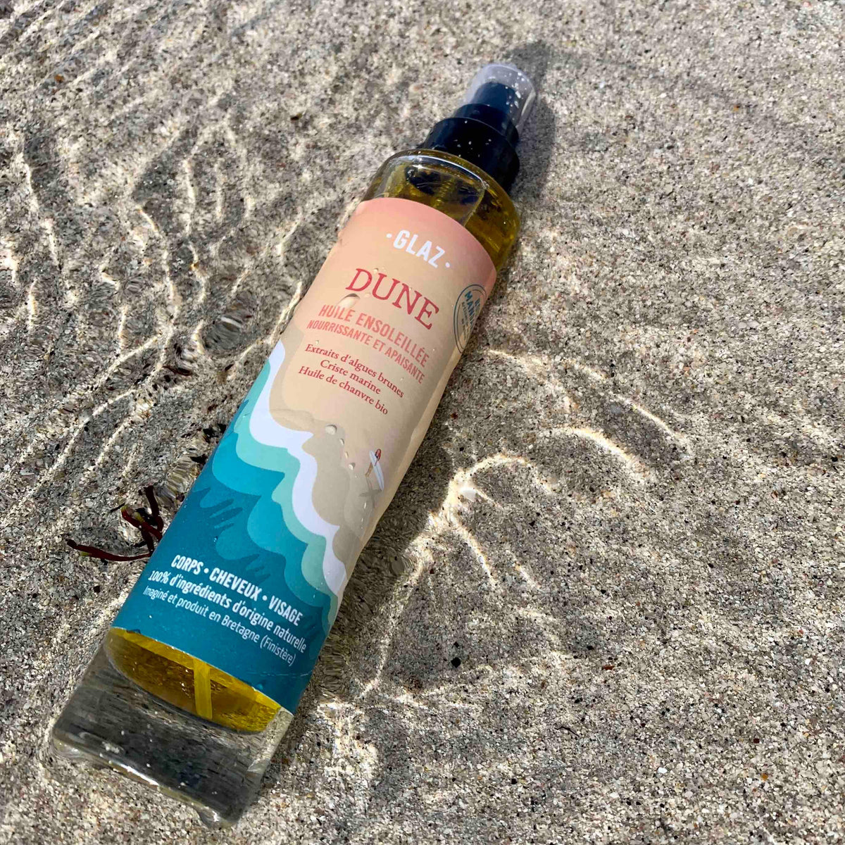 Huile sèche dune pour le corps et les cheveux sur le sable avec la mer