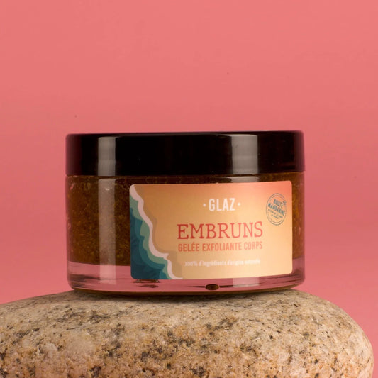 Le gommage pour le corps Embruns aux ingrédients naturels et Bretons dans un pot en verre transparent fermé sur un fond rose uni