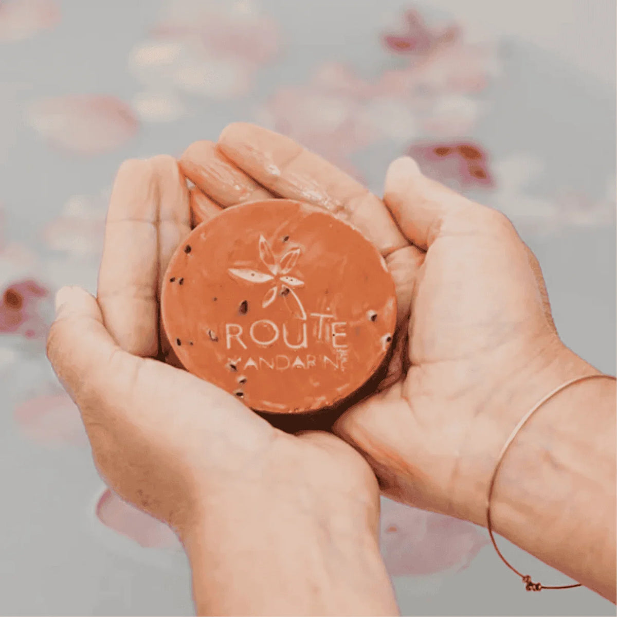 savon samourai dans les mains d'une femme au dessus d'une baignoire avec des fleurs